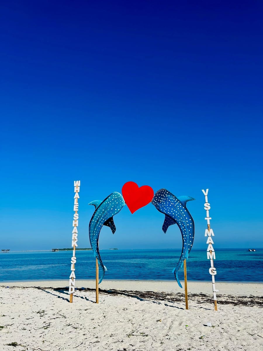 Zwei Walhai-Skulpturen halten am Strand ein rotes Herz